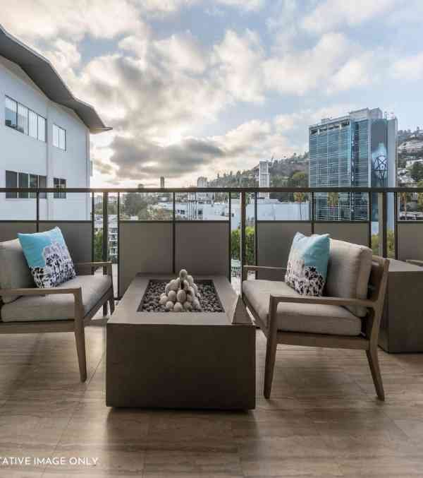 A king-size balcony at the DLF Arbour project, featuring two comfortable couches and a fire pit, offers a spacious deck for outdoor enjoyment.