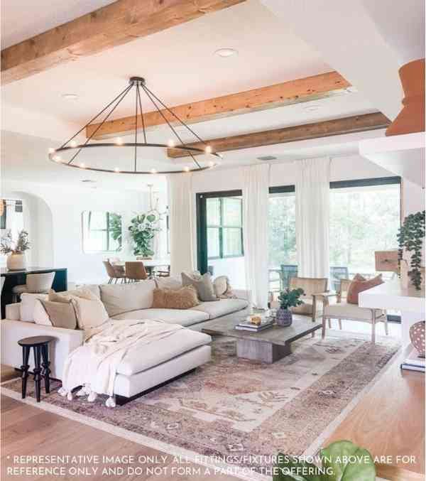 A spacious living room in DLF The Arbour Ultra Luxury Apartments, featuring a large white couch under a stylish wooden ceiling.